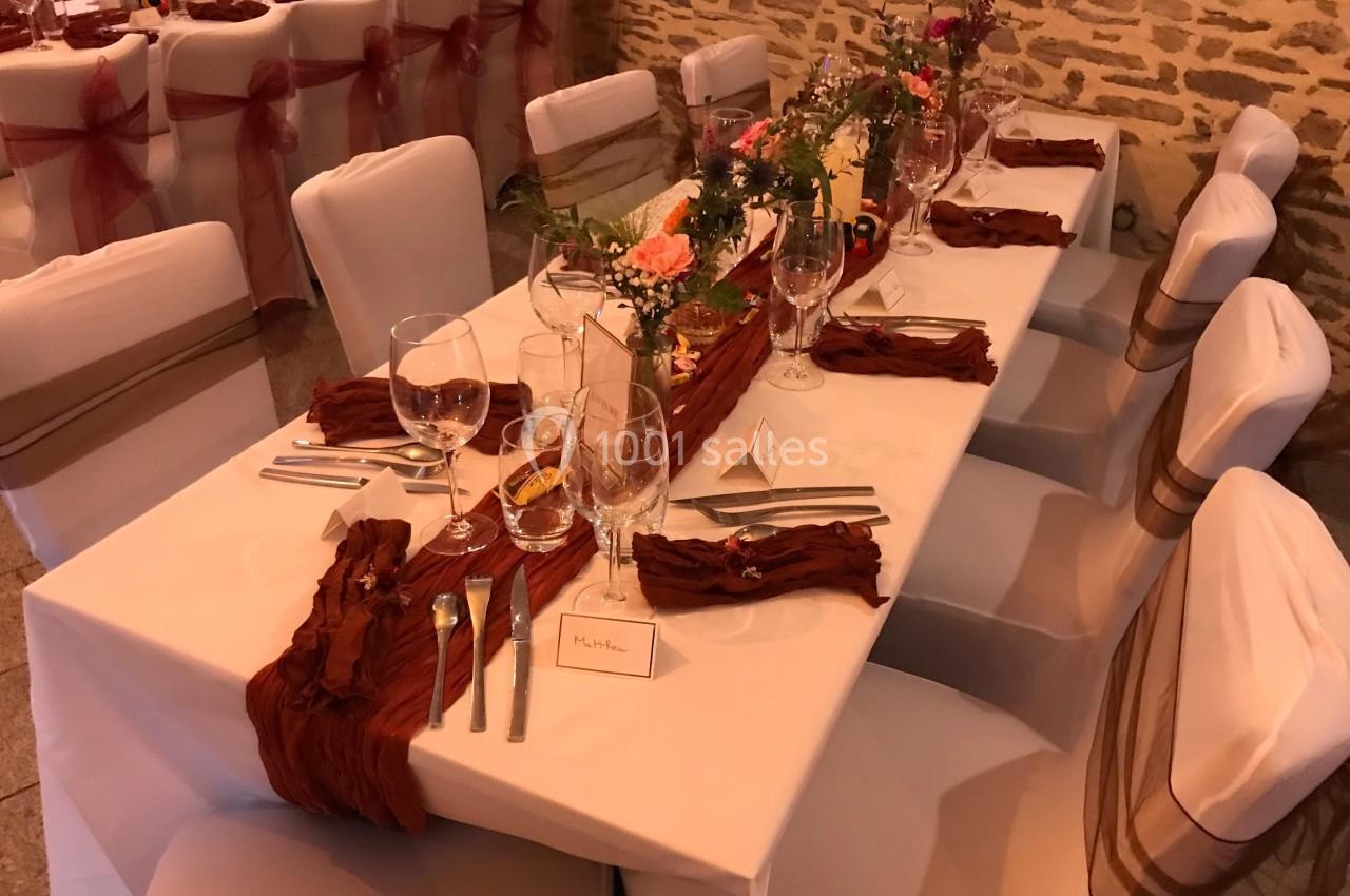 Table de réception décorée avec nappes blanches, chemins de table rouges, vaisselle élégante et compositions florales.