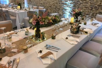 Une femme en robe de mariée est assise sur un tapis dans un jardin, tenant un bouquet de fleurs séchées.