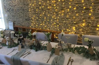 Une femme en robe de mariée est assise sur un tapis dans un jardin, tenant un bouquet de fleurs séchées.