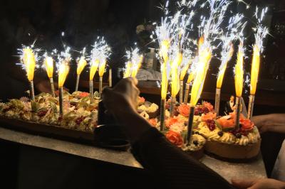 Une femme en robe de mariée est assise sur un tapis dans un jardin, tenant un bouquet de fleurs séchées.