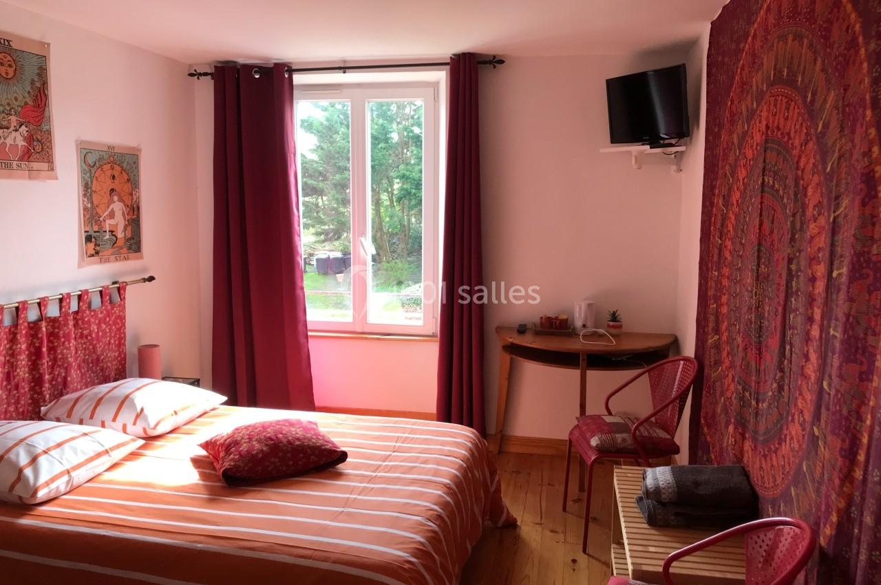 Chambre lumineuse avec lit double, décorée de motifs colorés, équipée d'une télévision et d'une fenêtre donnant sur un…