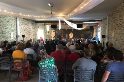 Une femme en robe de mariée est assise sur un tapis dans un jardin, tenant un bouquet de fleurs séchées.