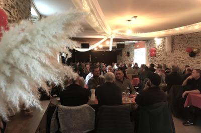 Une femme en robe de mariée est assise sur un tapis dans un jardin, tenant un bouquet de fleurs séchées.