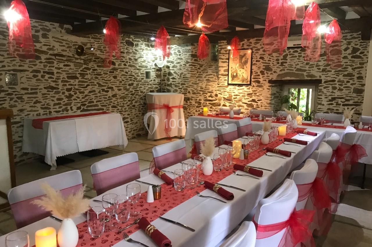 Salle de réception décorée avec des nappes blanches et rouges, des chaises assorties et des suspensions en tissu rouge.