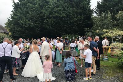 Une femme en robe de mariée est assise sur un tapis dans un jardin, tenant un bouquet de fleurs séchées.