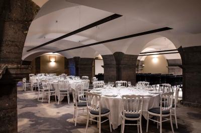 Chambre élégante avec lit double, fauteuil, rideaux beiges, tableaux encadrés et lumière naturelle entrant par une grande…