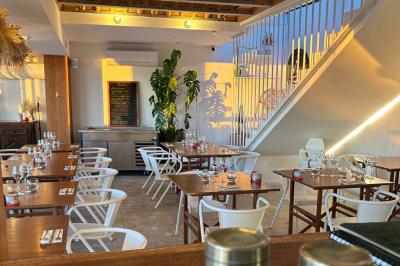 Façade d'un bâtiment avec une enseigne ’V&VICOTI’ en lettres blanches, terrasse en bois et mobilier visible en arrière-plan.