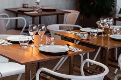 Façade d'un bâtiment avec une enseigne ’V&VICOTI’ en lettres blanches, terrasse en bois et mobilier visible en arrière-plan.