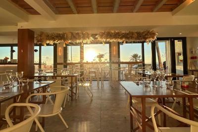 Façade d'un bâtiment avec une enseigne ’V&VICOTI’ en lettres blanches, terrasse en bois et mobilier visible en arrière-plan.