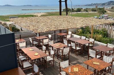 Façade d'un bâtiment avec une enseigne ’V&VICOTI’ en lettres blanches, terrasse en bois et mobilier visible en arrière-plan.