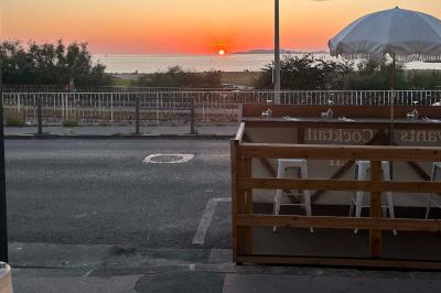 Façade d'un bâtiment avec une enseigne ’V&VICOTI’ en lettres blanches, terrasse en bois et mobilier visible en arrière-plan.