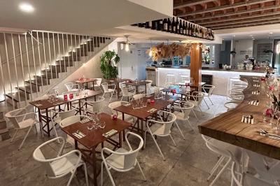 Façade d'un bâtiment avec une enseigne ’V&VICOTI’ en lettres blanches, terrasse en bois et mobilier visible en arrière-plan.