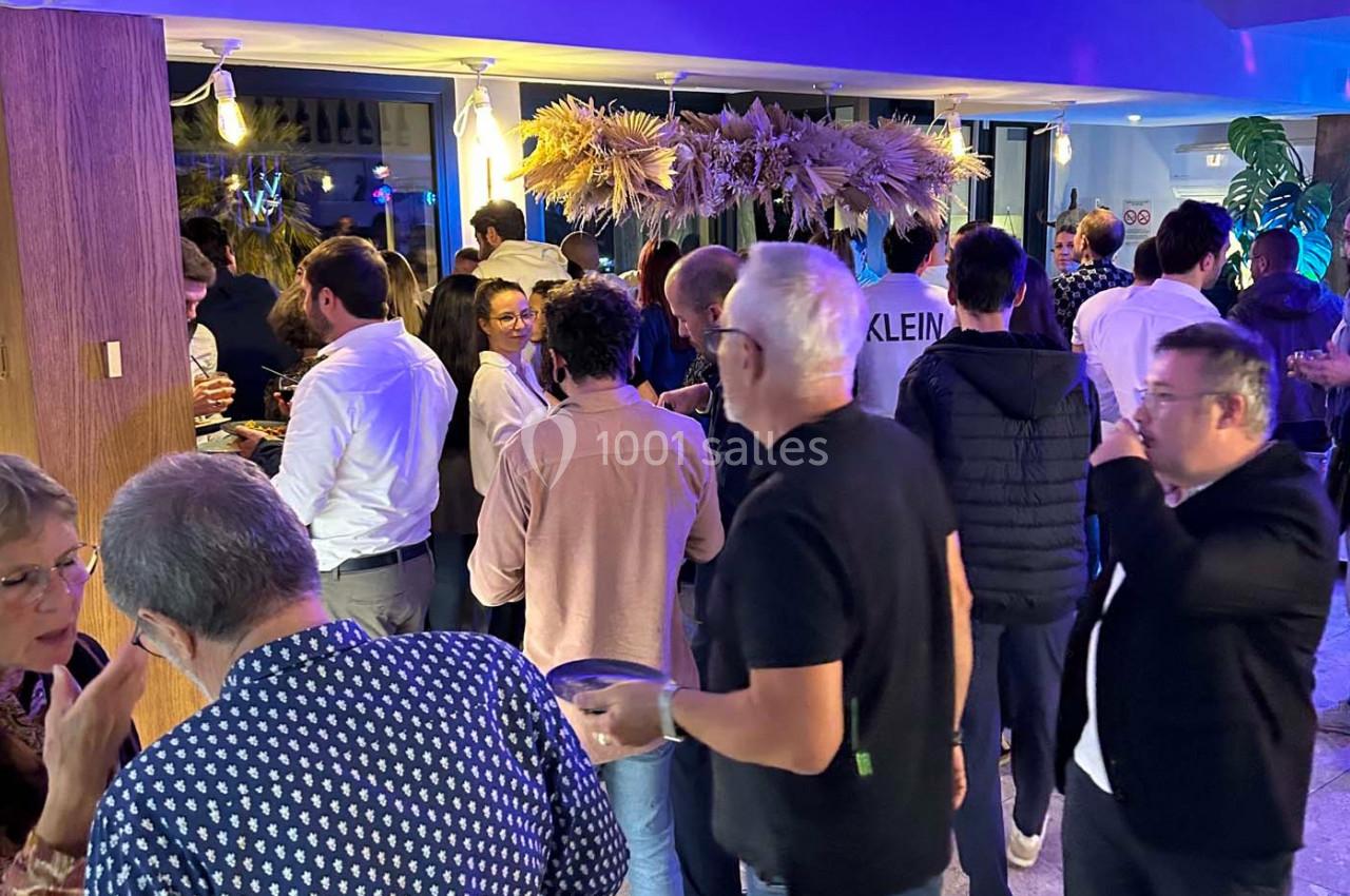 Groupe de personnes discutant et partageant un moment convivial dans un espace intérieur décoré de plantes et lumières.