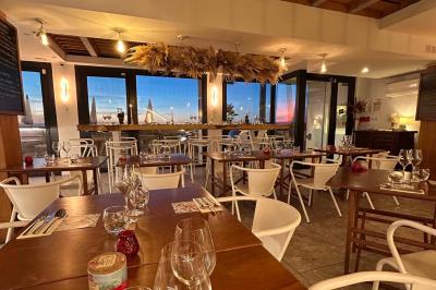 Façade d'un bâtiment avec une enseigne ’V&VICOTI’ en lettres blanches, terrasse en bois et mobilier visible en arrière-plan.