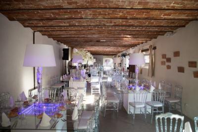 Vue aérienne d'une ferme en pierre entourée de champs verdoyants, avec des personnes rassemblées dans la cour.