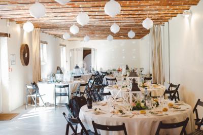 Vue aérienne d'une ferme en pierre entourée de champs verdoyants, avec des personnes rassemblées dans la cour.