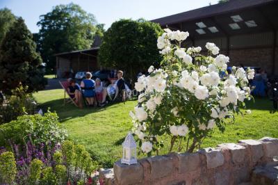 Vue aérienne d'une ferme en pierre entourée de champs verdoyants, avec des personnes rassemblées dans la cour.