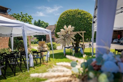 Vue aérienne d'une ferme en pierre entourée de champs verdoyants, avec des personnes rassemblées dans la cour.