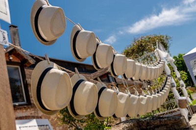 Vue aérienne d'une ferme en pierre entourée de champs verdoyants, avec des personnes rassemblées dans la cour.