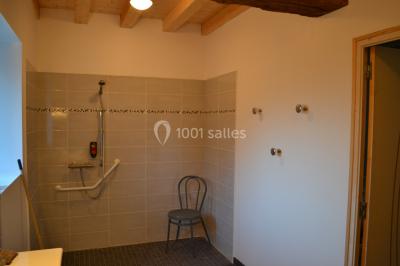 Allée bordée de végétation dense avec un château gonflable coloré visible à gauche et des bâtiments en arrière-plan.