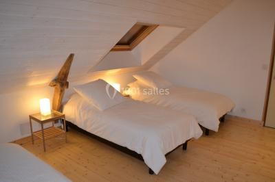 Allée bordée de végétation dense avec un château gonflable coloré visible à gauche et des bâtiments en arrière-plan.