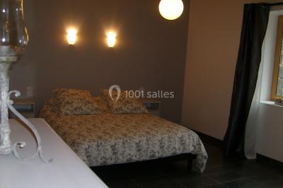 Allée bordée de végétation dense avec un château gonflable coloré visible à gauche et des bâtiments en arrière-plan.