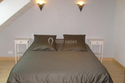 Allée bordée de végétation dense avec un château gonflable coloré visible à gauche et des bâtiments en arrière-plan.