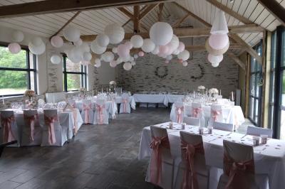 Allée bordée de végétation dense avec un château gonflable coloré visible à gauche et des bâtiments en arrière-plan.