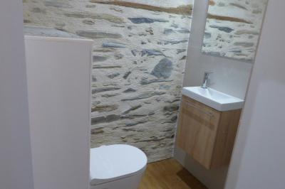 Allée bordée de végétation dense avec un château gonflable coloré visible à gauche et des bâtiments en arrière-plan.