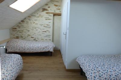 Allée bordée de végétation dense avec un château gonflable coloré visible à gauche et des bâtiments en arrière-plan.