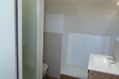 Allée bordée de végétation dense avec un château gonflable coloré visible à gauche et des bâtiments en arrière-plan.