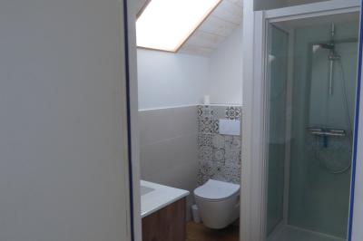 Allée bordée de végétation dense avec un château gonflable coloré visible à gauche et des bâtiments en arrière-plan.