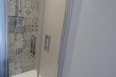 Allée bordée de végétation dense avec un château gonflable coloré visible à gauche et des bâtiments en arrière-plan.