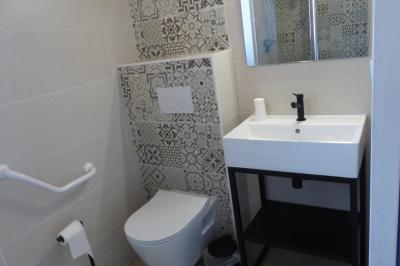 Allée bordée de végétation dense avec un château gonflable coloré visible à gauche et des bâtiments en arrière-plan.