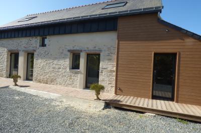Allée bordée de végétation dense avec un château gonflable coloré visible à gauche et des bâtiments en arrière-plan.