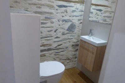 Allée bordée de végétation dense avec un château gonflable coloré visible à gauche et des bâtiments en arrière-plan.