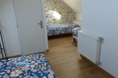 Allée bordée de végétation dense avec un château gonflable coloré visible à gauche et des bâtiments en arrière-plan.