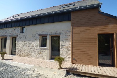 Allée bordée de végétation dense avec un château gonflable coloré visible à gauche et des bâtiments en arrière-plan.