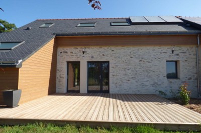 Allée bordée de végétation dense avec un château gonflable coloré visible à gauche et des bâtiments en arrière-plan.