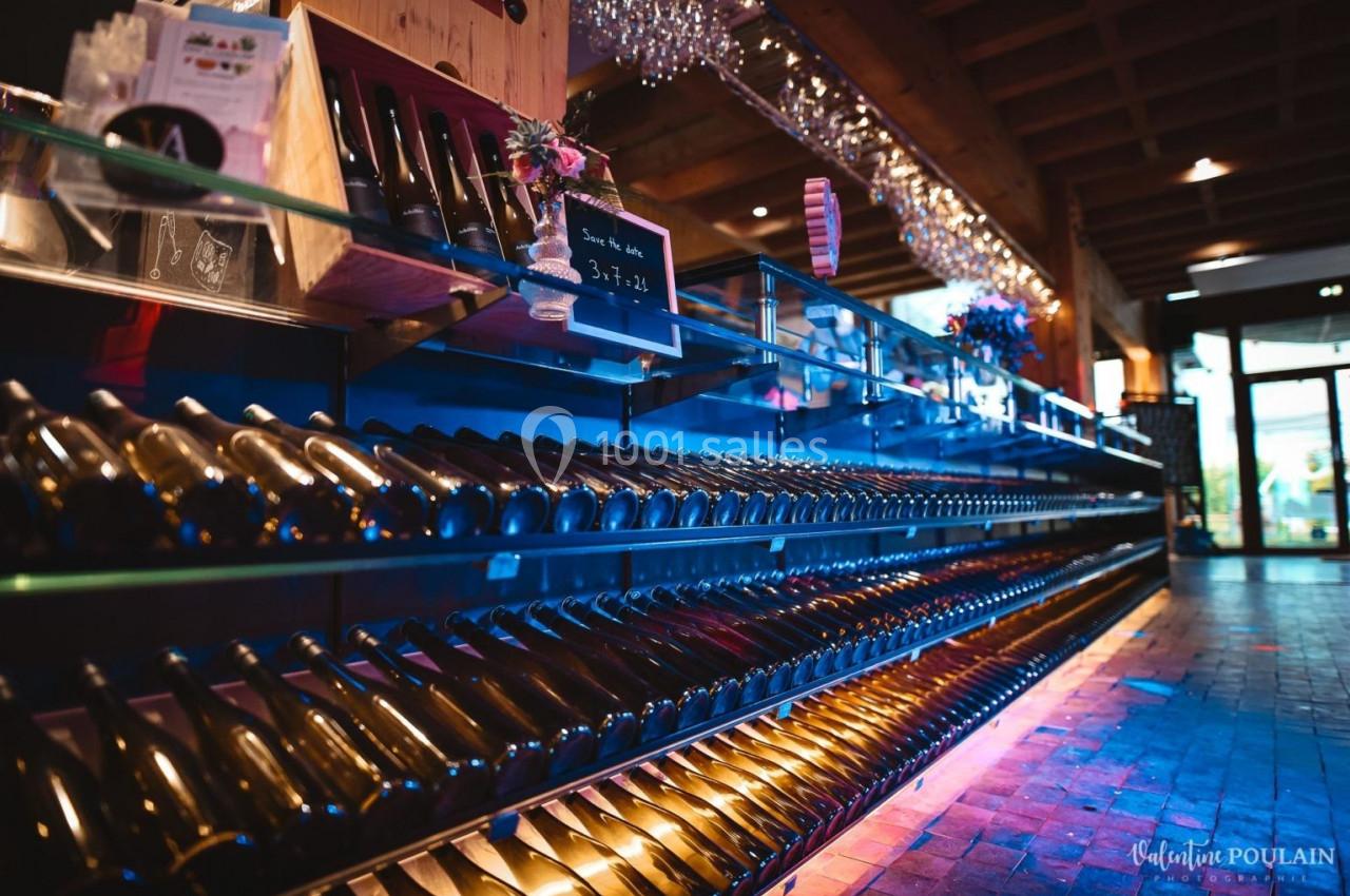 Rayonnage de bouteilles de vin alignées dans un magasin avec éclairage tamisé et décoration en arrière-plan.