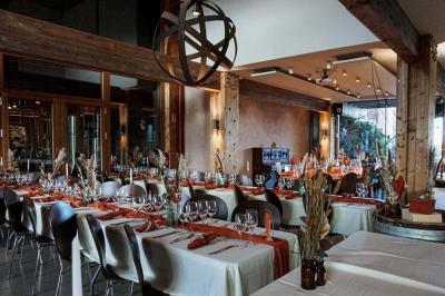 Façade d'un bâtiment en bois et crépi rose avec le mot ’Achillée’, sous un ciel partiellement nuageux.