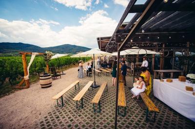 Façade d'un bâtiment en bois et crépi rose avec le mot ’Achillée’, sous un ciel partiellement nuageux.