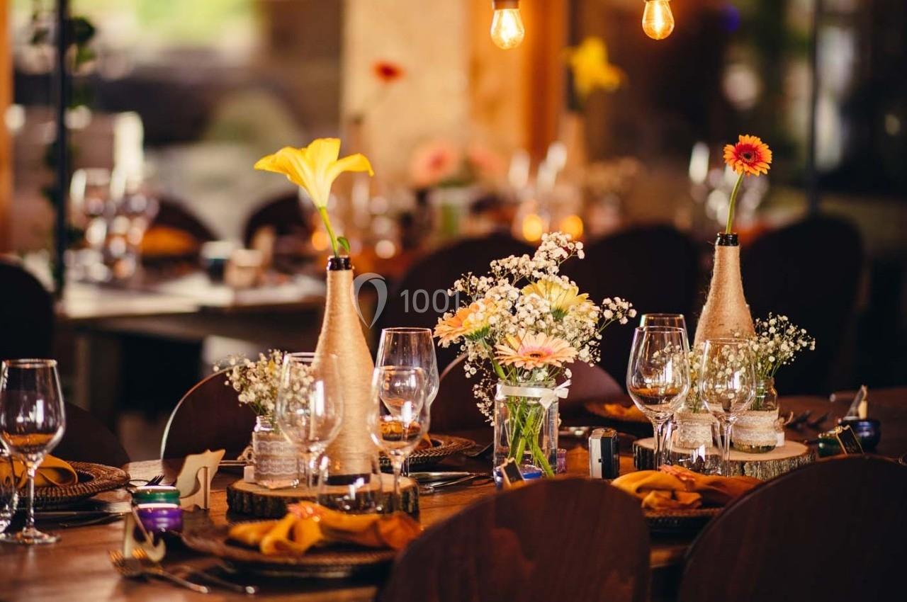 Table décorée avec des fleurs, des verres à pied et des bougies dans une ambiance chaleureuse et tamisée.