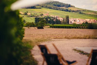 Façade d'un bâtiment en bois et crépi rose avec le mot ’Achillée’, sous un ciel partiellement nuageux.