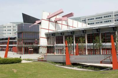 Vue aérienne d'un campus avec des bâtiments, parkings, hôtels et accès direct aux transports en commun.