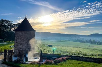 Paysage rural avec une clôture en bois, des champs verdoyants, des arbres et un bâtiment en pierre sous un ciel…
