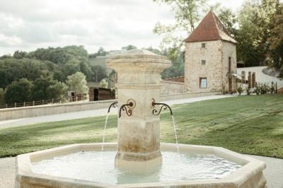 Paysage rural avec une clôture en bois, des champs verdoyants, des arbres et un bâtiment en pierre sous un ciel…