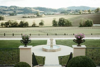 Paysage rural avec une clôture en bois, des champs verdoyants, des arbres et un bâtiment en pierre sous un ciel…