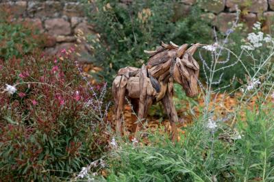 Paysage rural avec une clôture en bois, des champs verdoyants, des arbres et un bâtiment en pierre sous un ciel…