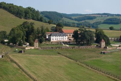 Paysage rural avec une clôture en bois, des champs verdoyants, des arbres et un bâtiment en pierre sous un ciel…